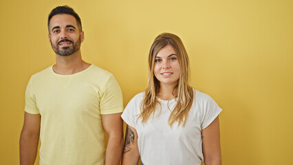 Man and woman couple smiling confident standing together over isolated yellow background