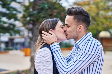 Fototapeta premium Man and woman couple hugging each other kissing at park