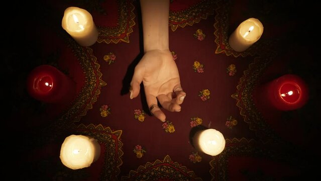 Top view, woman chiromancer holding a female clients hand and reading her lines on open palm.