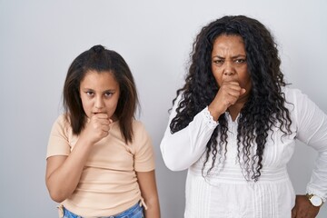 Mother and young daughter standing over white background feeling unwell and coughing as symptom for cold or bronchitis. health care concept.