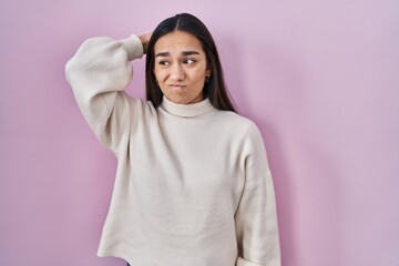Young south asian woman standing over pink background confuse and wondering about question....
