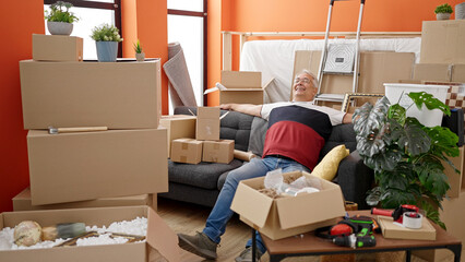 Middle age man with grey hair resting sitting on the sofa at new home