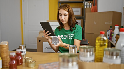 Young woman volunteer using touchpad checking products at charity center