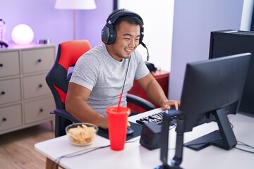 Young chinese man streamer playing video game using computer at gaming room