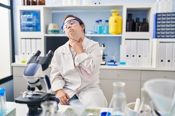 Fototapeta premium Hispanic girl with down syndrome working at scientist laboratory touching painful neck, sore throat for flu, clod and infection