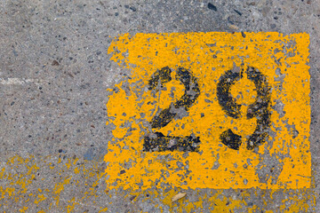 Schwarze Zahl 29 in gelbem Quadrat, auf Betonhallenboden aufgemalt.