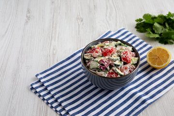 Fototapeta na wymiar Homemade Tomato Cucumber Feta Salad in a Bowl, side view. Copy space.