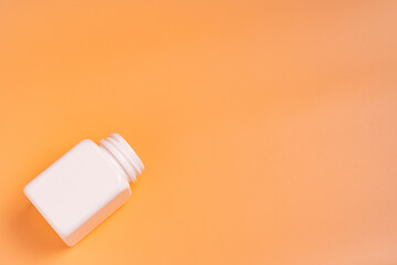 White plastic bottle on orange background with copy space. Top view.