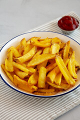 Homemade French Fries with Ketchup on a Plate, side view.