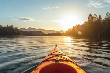 Foto op Canvas Front of an orange kayak on a lake at sunset. The kayak is pointed towards the horizon and the sun is setting behind the mountains in the background, golden glow © Florian