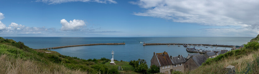 Port-en-Bessin-Huppain, France - 07 24 2023: Panoramic view of the harbor, houses and the sea from the cliffs.