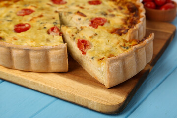 Delicious homemade cheese quiche on light blue wooden table, closeup