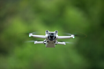 Flying drone with blurred green background.