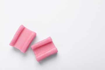 Tasty pink chewing gums on white background, flat lay. Space for text