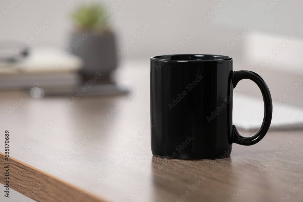 Sticker Black ceramic mug on wooden table at workplace. Space for text