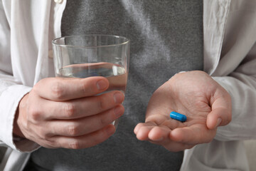 Man with glass of water and pill, closeup