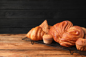 Different tasty freshly baked pastries on wooden table, space for text