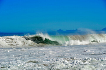  powerful cross ocean wave breaking during the day on the beach