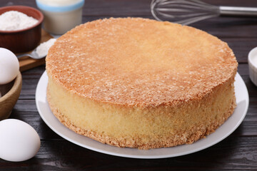 Plate with delicious sponge cake on dark wooden table, closeup