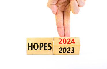 2024 hopes new year symbol. Businessman turns a wooden cube and changes words Hopes 2023 to Hopes 2024. Beautiful white background, copy space. Business 2024 hopes new year concept.