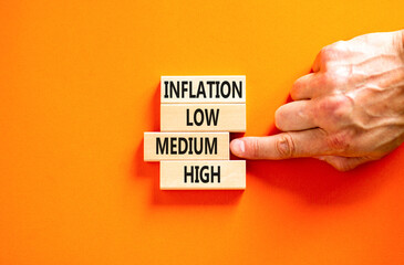 Medium inflation symbol. Concept word Inflation low medium high on wooden block. Businessman hand. Beautiful orange table orange background. Business time to medium inflation concept. Copy space.