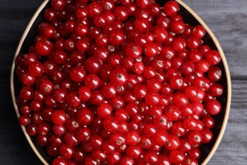 Ripe red currants in bowl on wooden rustic table, top view