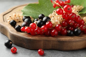Different fresh ripe currants and green leaf on table, closeup