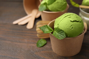 Paper cups with tasty matcha ice cream on wooden table, closeup. Space for text