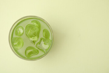 Glass of delicious iced matcha tea on green background, top view. Space for text