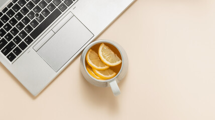 Laptop with cup of tea with lemon, copy space for design and branding. Home office template, office desktop, aesthetic workspace, top view