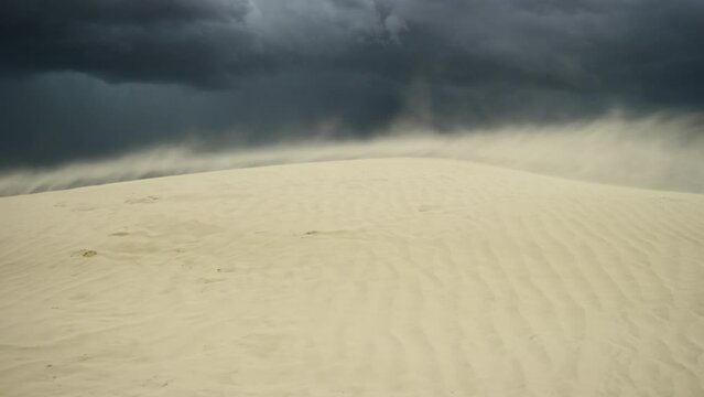 Sand blasts across dune during dramatic imposing thunderstorm