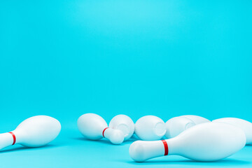 Minimalist photo of bowling pins over turquoise blue background. Image of white knocked down bowling pins with copy space.