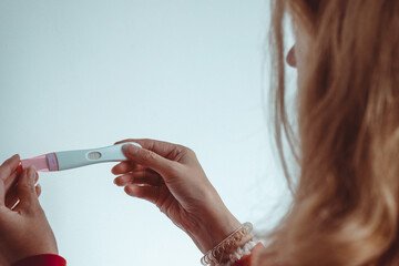 A female holds up a positive pregnancy test after undergoing multiple rounds of IVF treatment for...