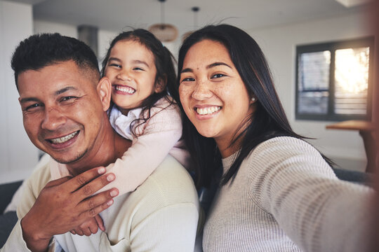 Selfie, happy and portrait of a family with a smile bonding in the living room of their home. Together, love and young happy parents taking a picture with their sweet girl child for memories in house