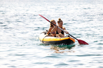 Two Female Friends Kayaking On The Sea