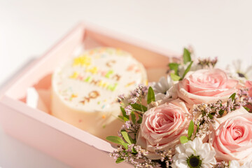 Cake with blooming roses in pink gift box on white background.