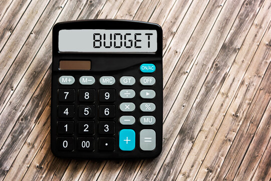 Calculator with word BUDGET on display and wooden background. Conceptual photo
