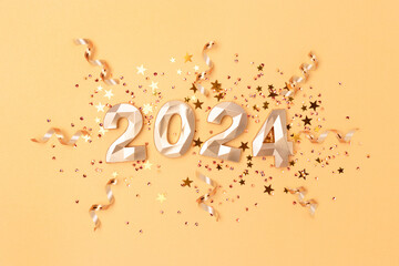 Obraz premium 2024 numbers, stars confetti and ribbons on a gold colored background. New Year festive composition.