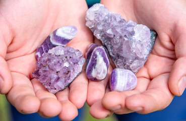 Natural mineral amethyst in hand. Semi-precious multi-colored stones, minerals close-up....