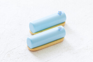 Vegan Blue Matcha cream dessert bar, decorated with a small flower. On cookies. Creamy dessert with the addition of blue powder of butterfly pea flowers. White background. Close up