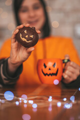 Portrait of candid authentic zoomer boy posing with jack lantern mug and sweets at halloween party