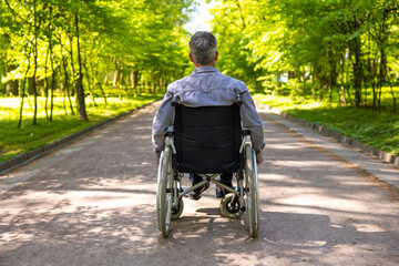 Man after car accident in wheelchair enjoying summertime in park.