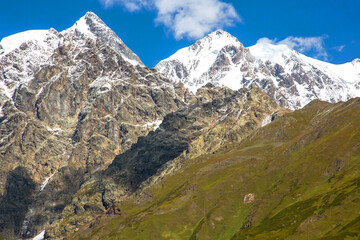 landscape of green grass and snowy mountains. Trekking and travel in Georgia