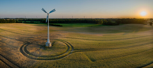 Aerial view of a small wind turbine gracefully spins above a gentle wheat field in atmosphere of a...