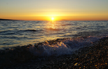 Pebble beach on the sea enlightened by sun during summer sunset