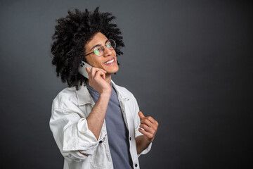 Young curly-haired guy talking on the phone and looking contented