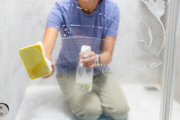 Woman remove hard water stains and deposits in bathroom