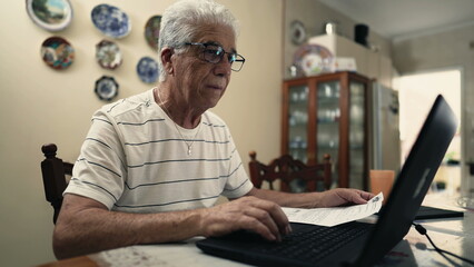 Senior Citizen Concerned Over Fine Debt Paper Beside Laptop, troubled retired man using computer to...