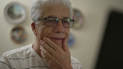 Senior man in front of computer screen, using modern technology. Gray-hair older person changing emotions from concerned to happy while browsing online activity