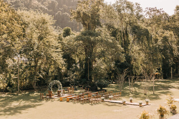 outdoor wedding ceremony with wooden benches and flower arch